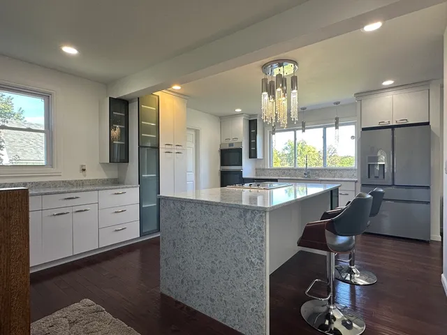 a large kitchen with granite countertop a large island in the center a sink a window stainless steel appliances and furniture