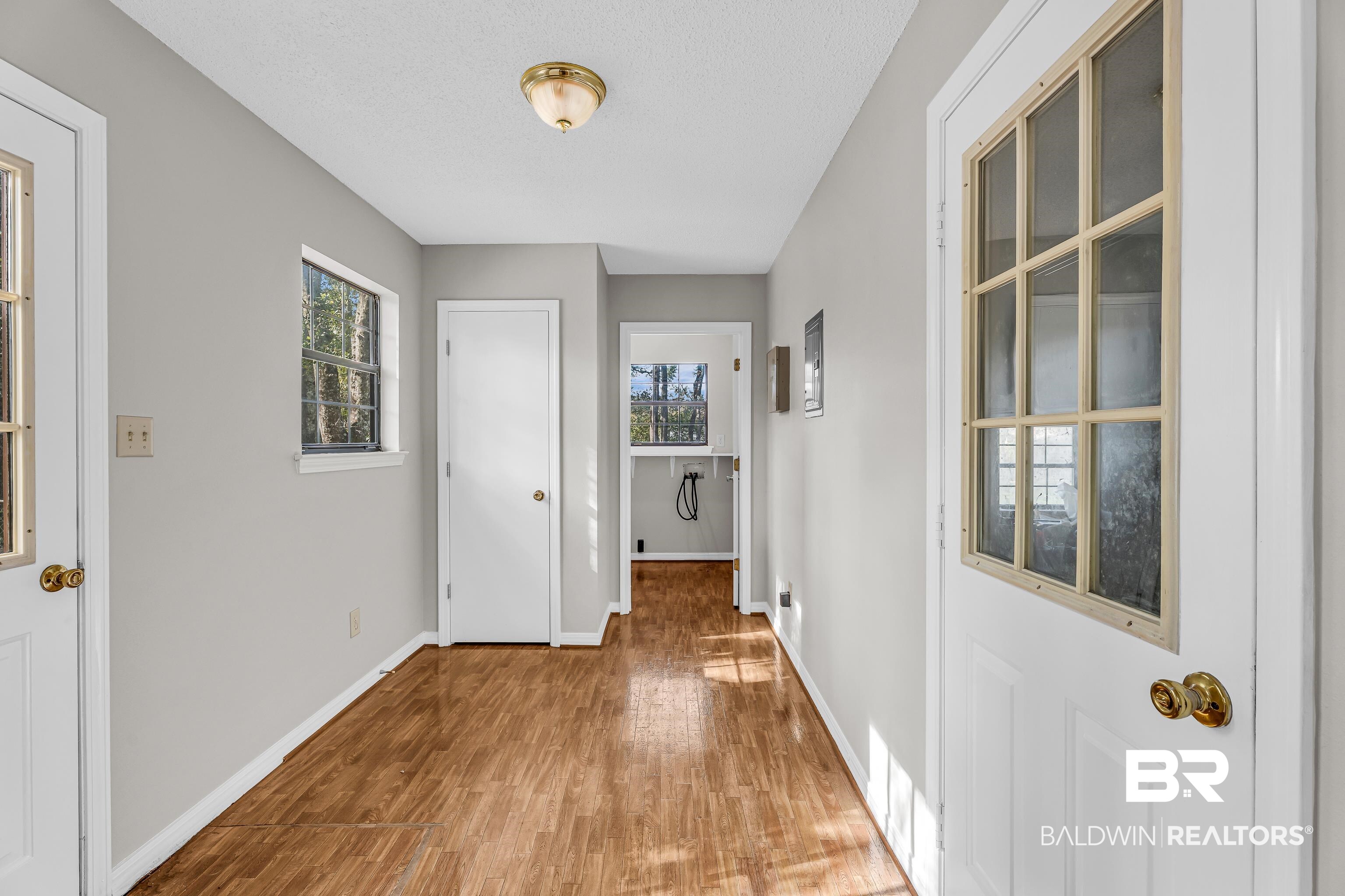 7787 Bellingrath Road Theodore, AL 36582 - Photo 18 of 36 Hallway featuring healthy amount of natural light, wood finished floors, and a textured ceiling