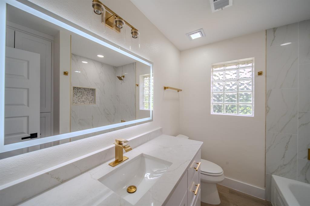 142 Ridgegate Drive Garland, TX 75040 - Photo 16 of 26 Bathroom featuring a white vanity with gold-finish hardware, an integrated sink, and a gold-finish faucet