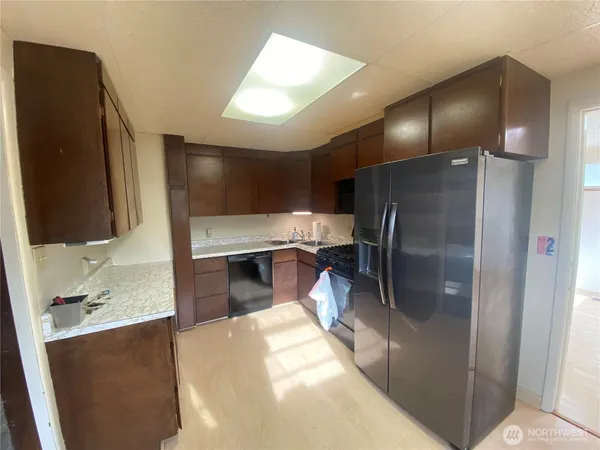 a kitchen with stainless steel appliances kitchen island granite countertop a refrigerator and a sink