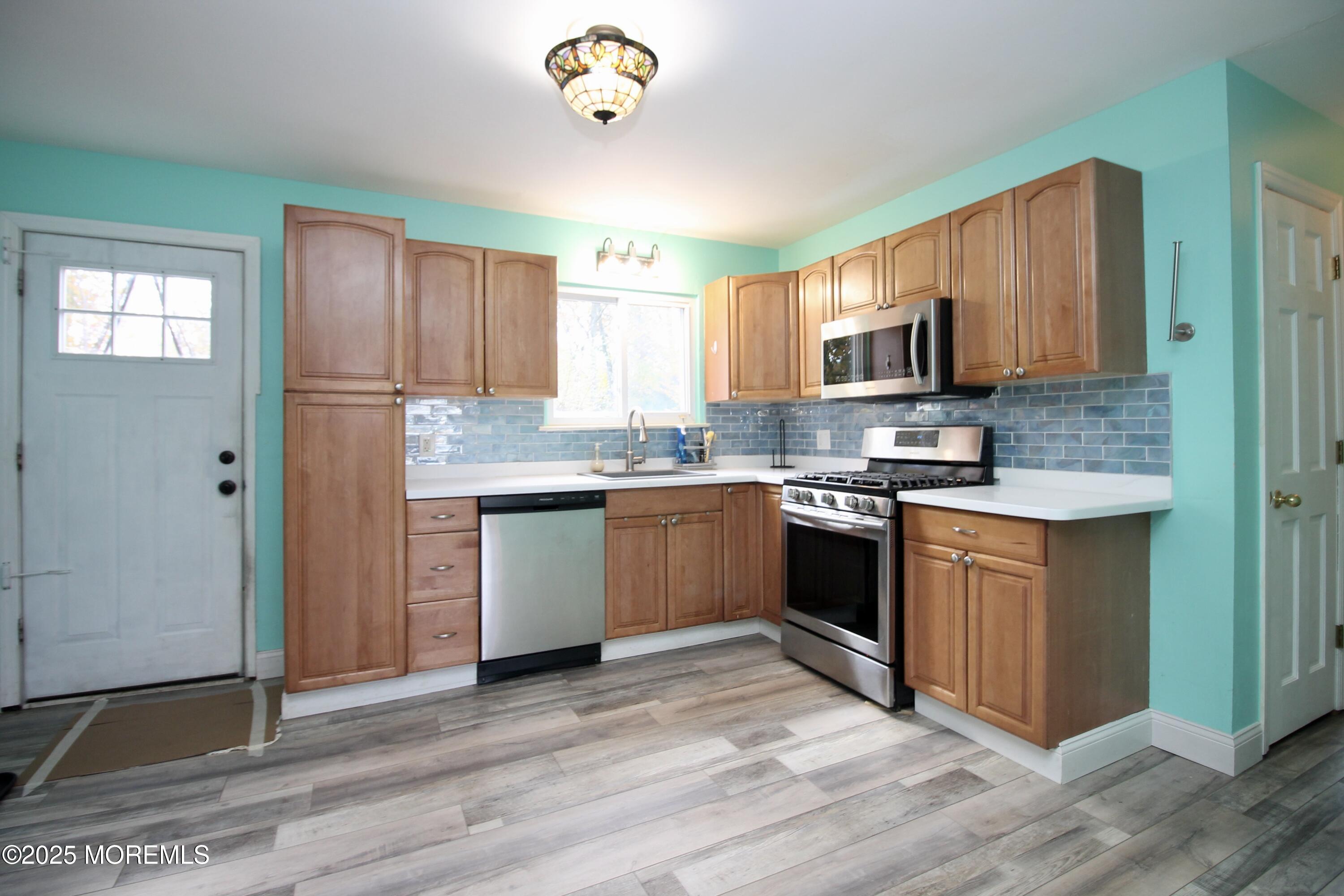 16 Maple Lane Howell, NJ 07731 - Photo 16 of 55 a kitchen with stainless steel appliances granite countertop a stove a sink dishwasher a microwave oven and a refrigerator with wooden floor