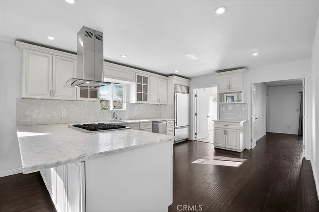 a kitchen with stainless steel appliances granite countertop a sink a stove a refrigerator and white cabinets with wooden floor