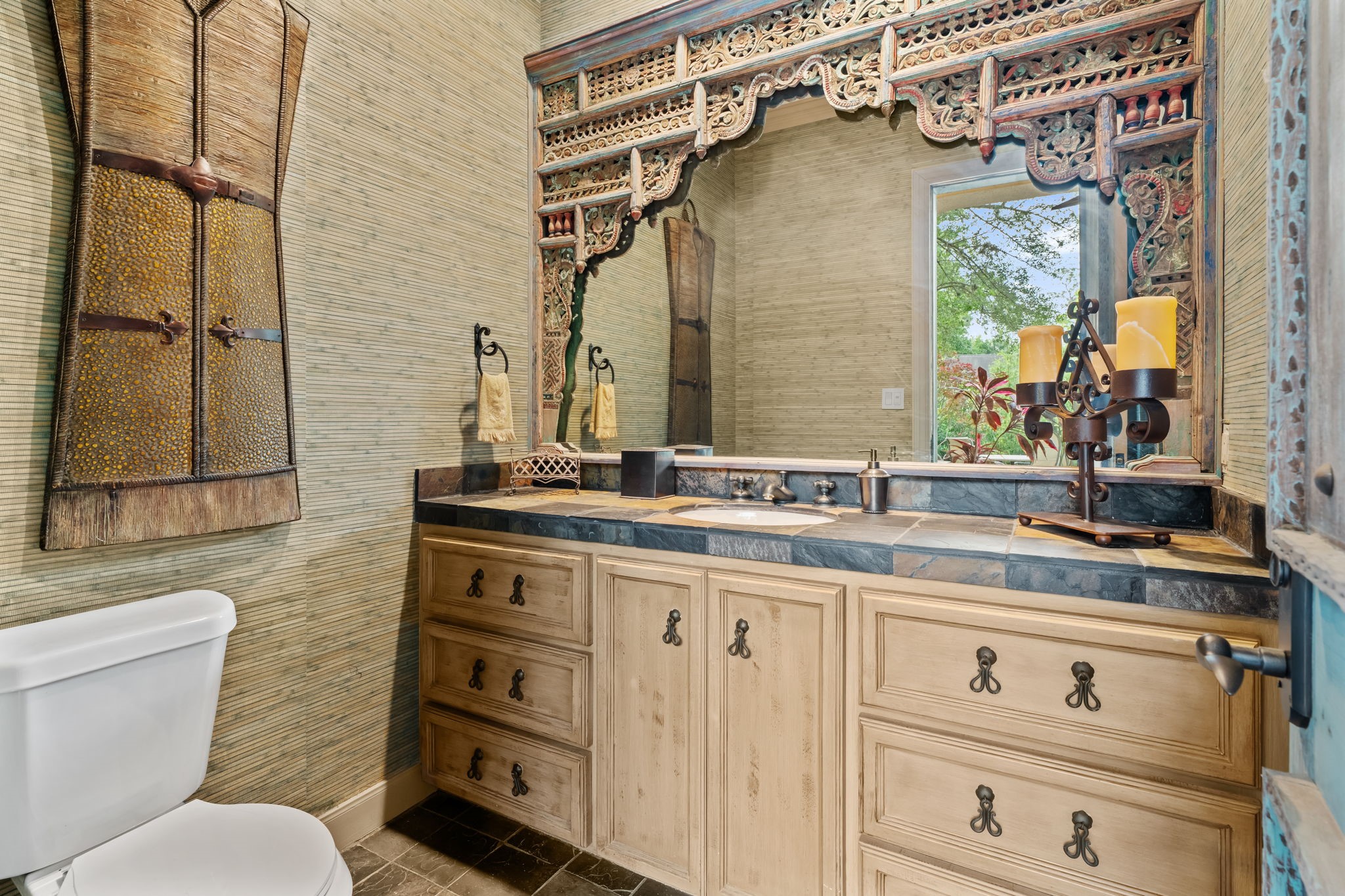 6 Mott Lane Houston, TX 77024 - Photo 44 of 50 Stylish pool bath featuring custom cabinetry, stone countertops, and an intricately carved statement mirror. Warm textures and elegant finishes create a unique, resort-style space perfectly suited for guests and outdoor entertaining.