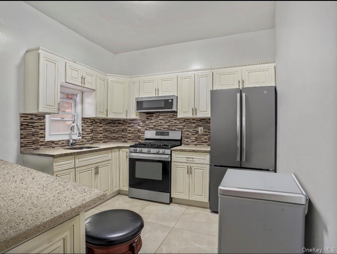 104-55 39th Avenue Queens, NY 11368 - Photo 5 of 14 a kitchen with granite countertop a sink stove and refrigerator