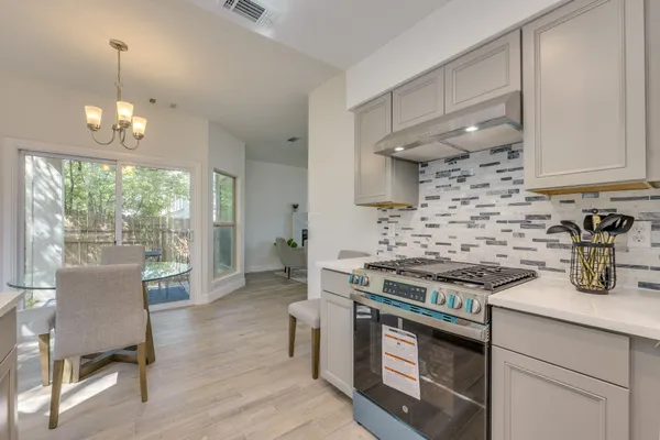 a kitchen with stainless steel appliances a stove a sink dishwasher a dining table and chairs with wooden floor