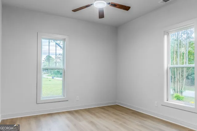 a view of an empty room with closet and wooden floor