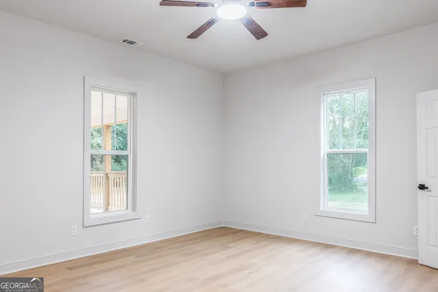 a view of an empty room with wooden floor and closet