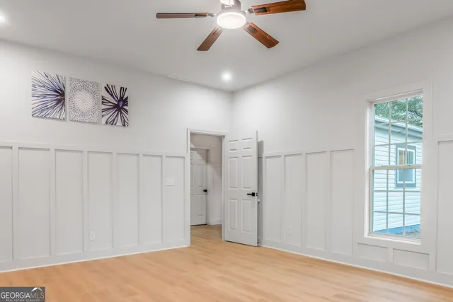 an empty room with wooden floor fan and windows