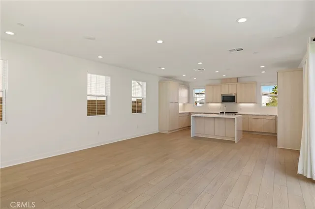 a large white kitchen with kitchen island a sink dishwasher a stove and white cabinets with wooden floor