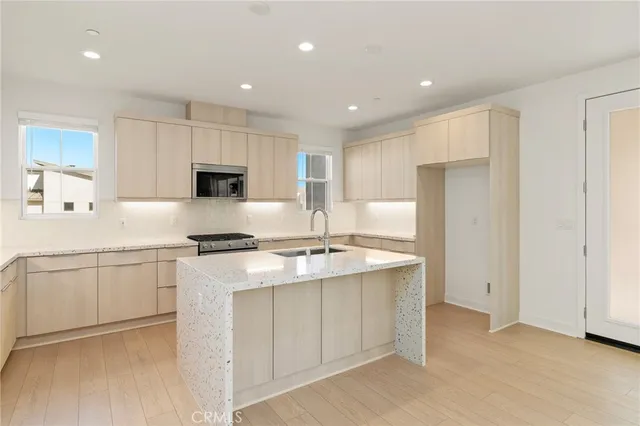 a kitchen with stainless steel appliances granite countertop a stove a refrigerator a sink a microwave and white cabinets