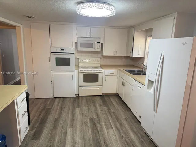 a kitchen with white cabinets and white appliances