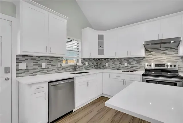 a kitchen with stainless steel appliances granite countertop a stove and white cabinets