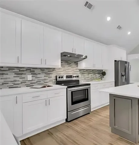 a kitchen with granite countertop white cabinets and stainless steel appliances