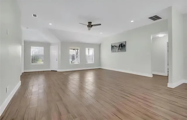 an empty room with wooden floor and windows