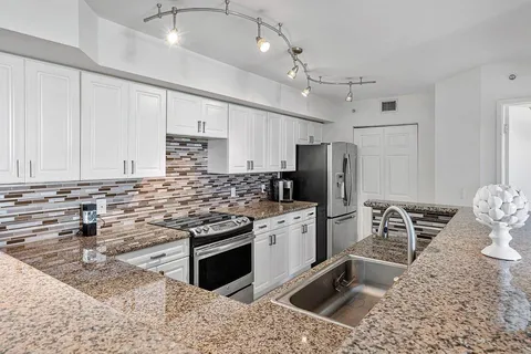 a kitchen with stainless steel appliances kitchen island granite countertop a sink stove and refrigerator