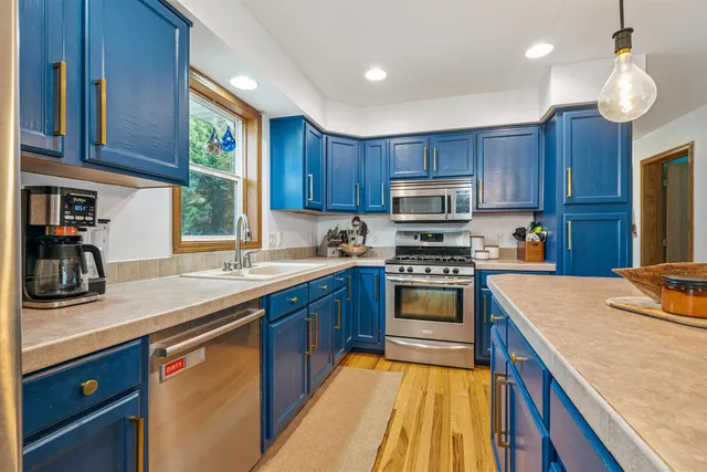 a kitchen with stainless steel appliances kitchen island a large island in the center and wooden cabinets