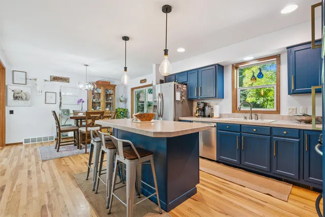 a kitchen with stainless steel appliances granite countertop wooden floors wooden cabinets a stove a sink and a center island