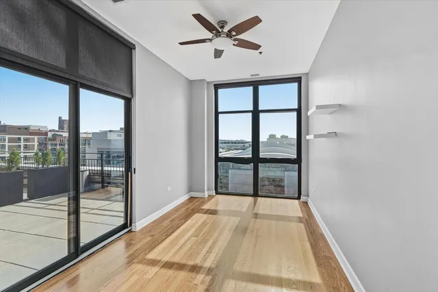 a view of empty room with wooden floor and fan