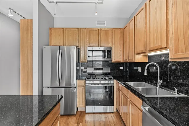 a kitchen with granite countertop a refrigerator a sink a stove and cabinets