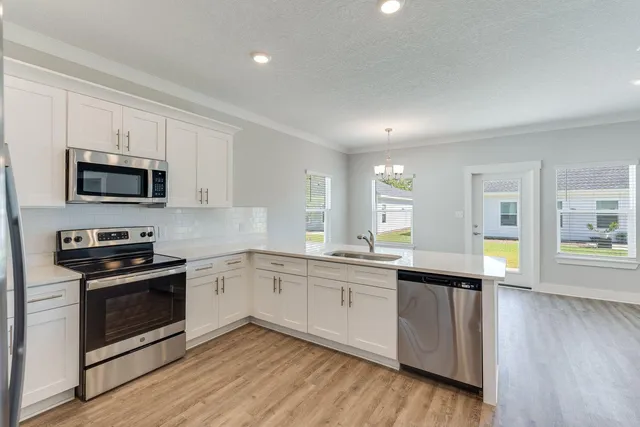 a large kitchen with cabinets wooden floor and stainless steel appliances