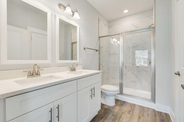 a bathroom with a double vanity sink toilet mirror and shower