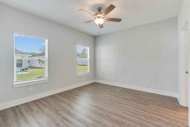 a view of an empty room with a window and wooden floor