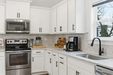 a kitchen with stainless steel appliances kitchen island granite countertop a sink a stove a refrigerator and cabinets