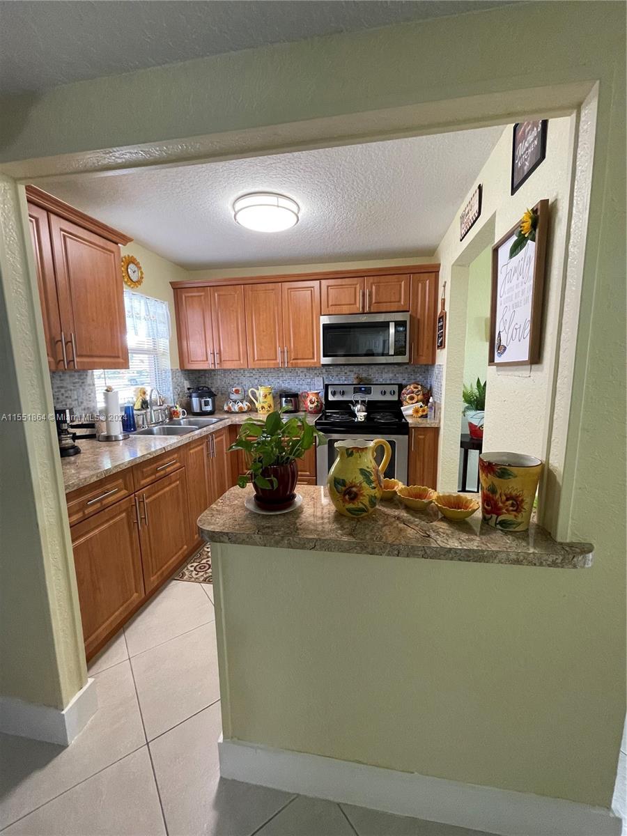 a kitchen with stainless steel appliances granite countertop a sink a stove counter space and a window
