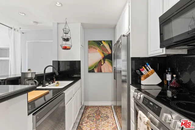 a kitchen with stainless steel appliances granite countertop a stove top oven a sink and a microwave