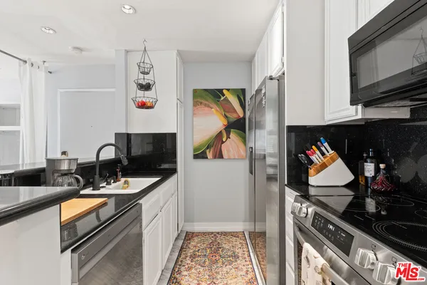 a kitchen with stainless steel appliances granite countertop a stove top oven a sink and a microwave