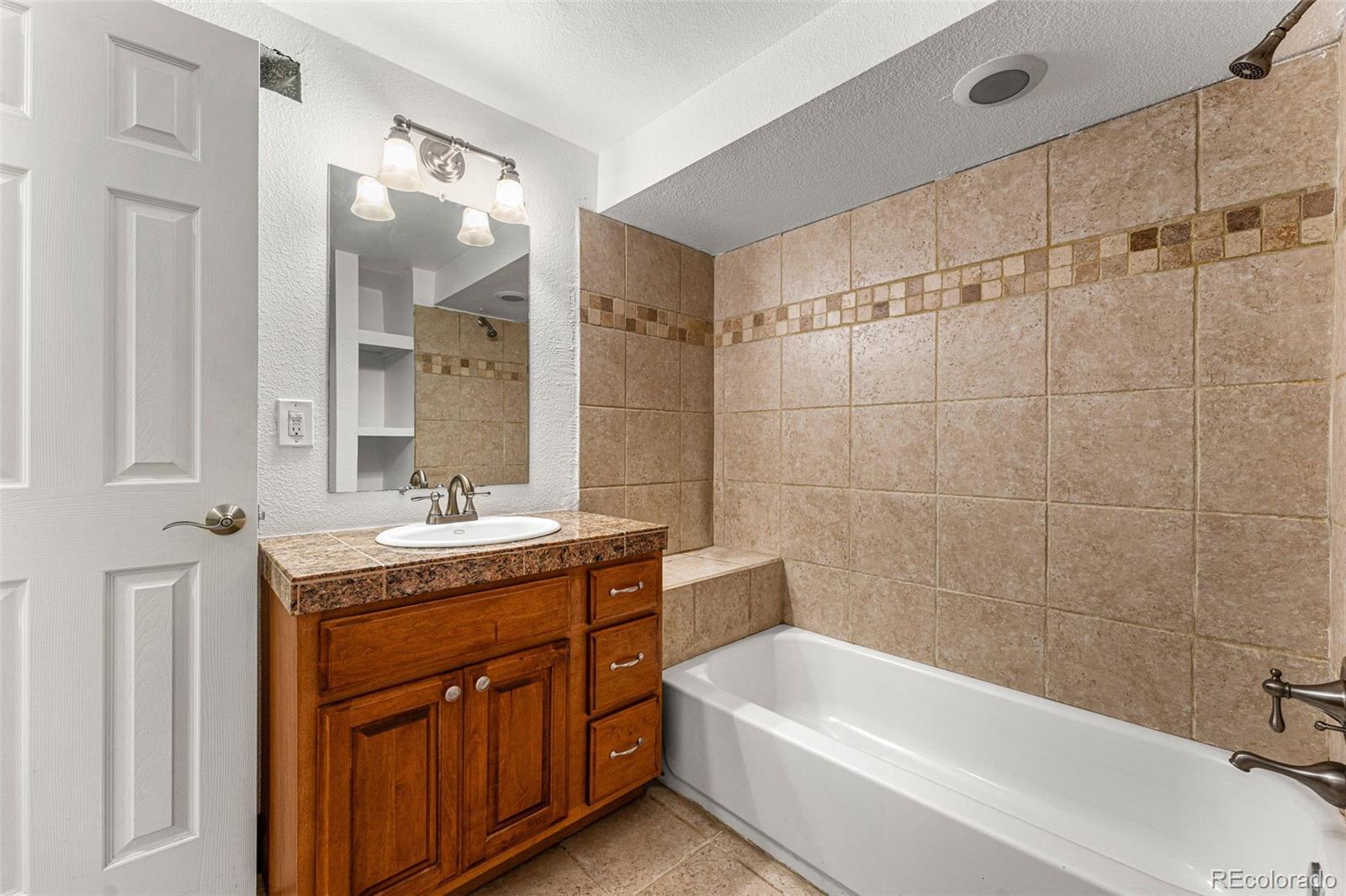 954 Jackson Street Denver, CO 80206 - Photo 22 of 37 a bathroom with a granite countertop sink a toilet a bathtub and shower