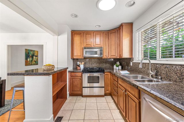 a kitchen with stainless steel appliances granite countertop sink stove top oven and cabinets