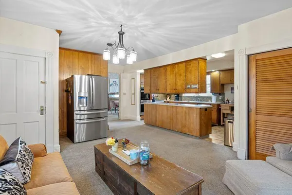 a kitchen with stainless steel appliances kitchen island granite countertop a refrigerator a oven a sink a dining table and chairs with wooden floor