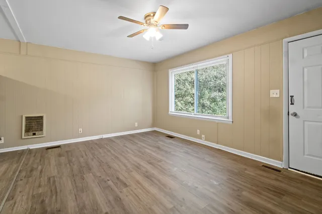 a view of an empty room with window and wooden floor