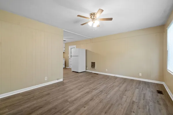 an empty room with wooden floor and ceiling fan