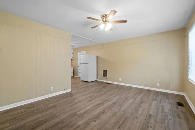 an empty room with wooden floor and ceiling fan