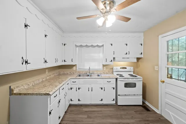 a kitchen with granite countertop a stove a sink and a refrigerator