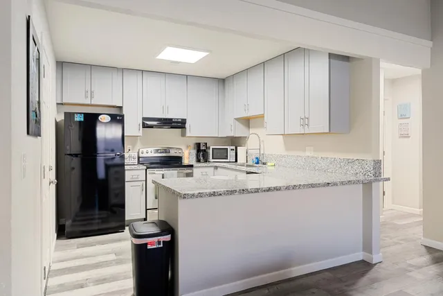 a kitchen with granite countertop kitchen island stainless steel appliances a refrigerator a stove a sink and a refrigerator