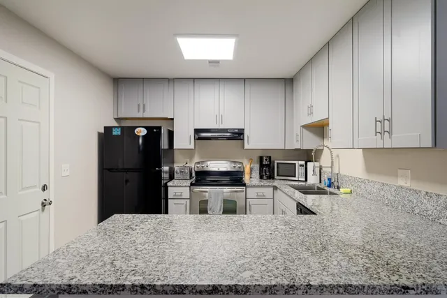 a kitchen with granite countertop a refrigerator and a stove top oven