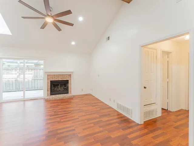 a view of an empty room with window and wooden floor