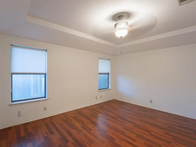 a view of empty room with wooden floor and fan