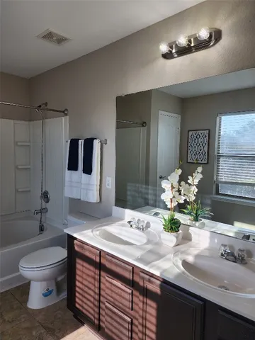 a bathroom with double vanity sinks a toilet a mirror and shower