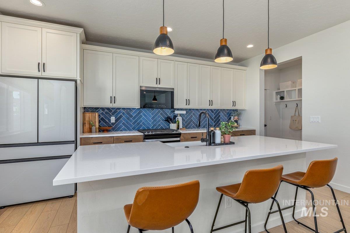 1380 West Chilitna Street Meridian, ID 83642 - Photo 8 of 50 Contemporary kitchen featuring a white countertop island, matte black faucet, and a vibrant blue herringbone tile backsplash