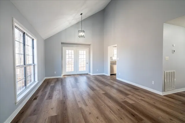 a view of an empty room with wooden floor fireplace and a window