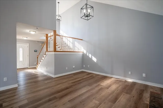 an empty room with wooden floor fireplace and windows