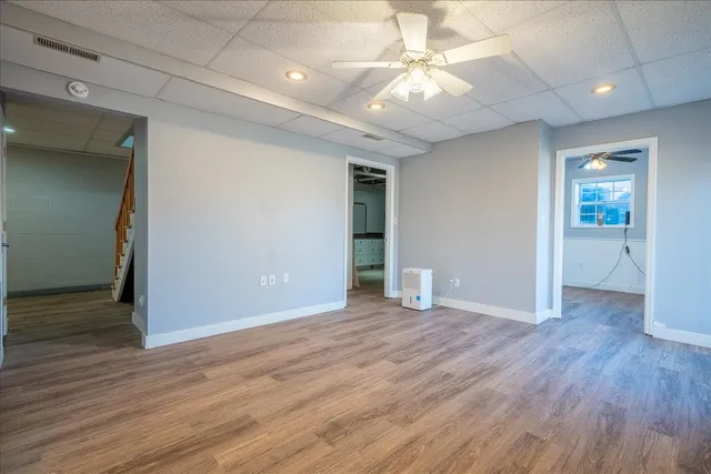 an empty room with wooden floor and fan