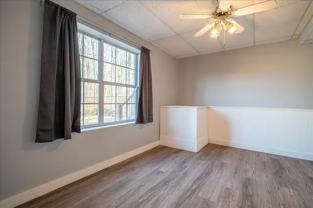 an empty room with wooden floor and chandelier fan