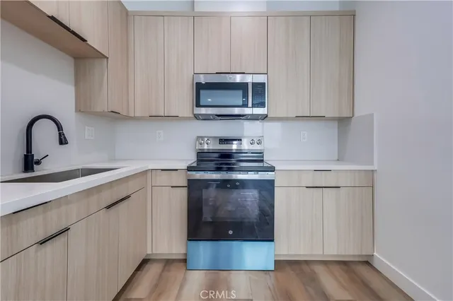 a kitchen with stainless steel appliances granite countertop a stove a sink and a white wooden cabinets