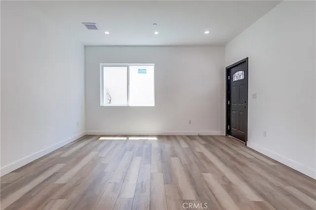 an empty room with wooden floor and a window