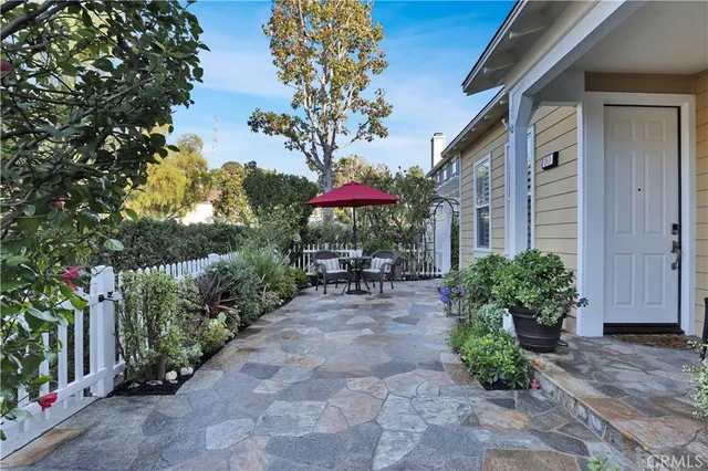 a view of a patio with table and chairs under an umbrella with potted plants